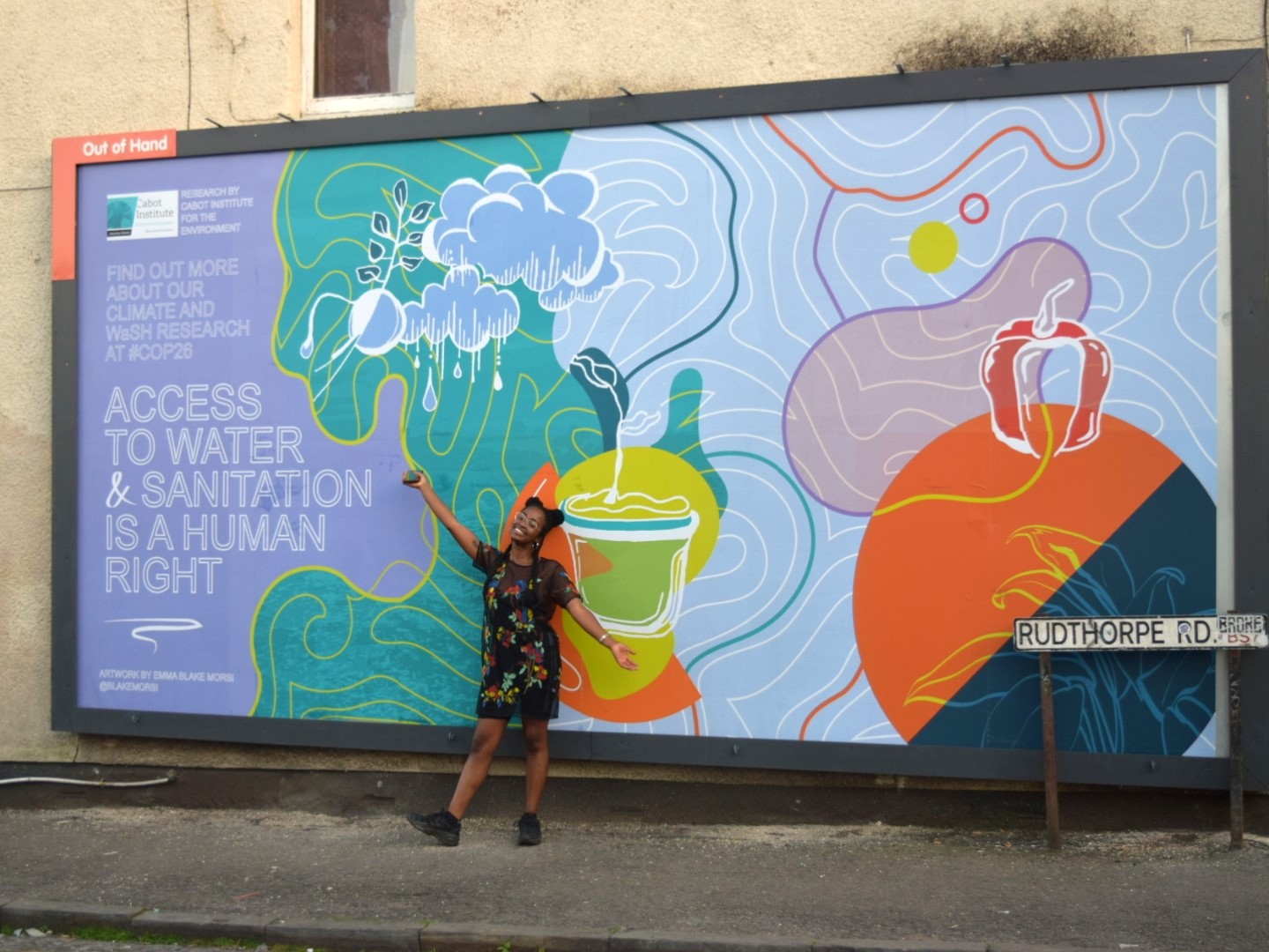 Emma Blake Morsi with one of the COP26 campaign billboard designs illustrating the importance of access to water and sanitation.