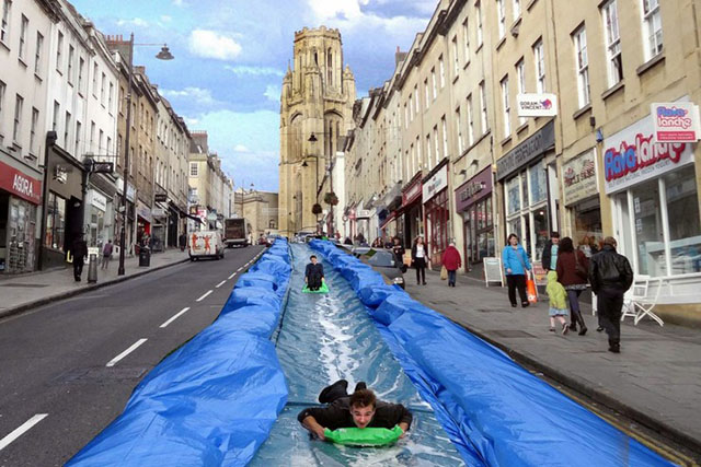 People descending plastic water slide running down Park Street, Bristol
