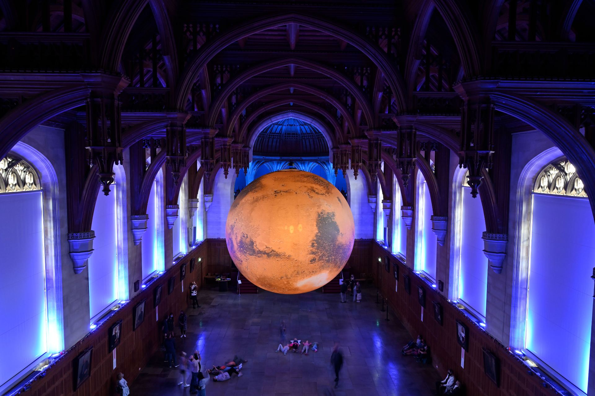 Visitor with pram and child passing underneath installation of Mars by Luke Jerram