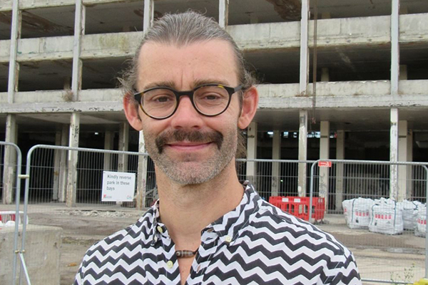 Artist Paul Hurley standing in front of the Royal Mail Sorting Office building during its demolition